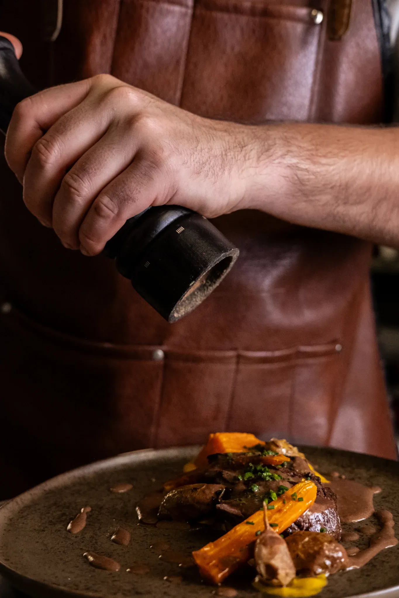 Antoine entrain de poivrer un onglet accompagné de carottes.